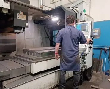 Operatore che utilizza un tornio CNC per una lavorazione meccanica